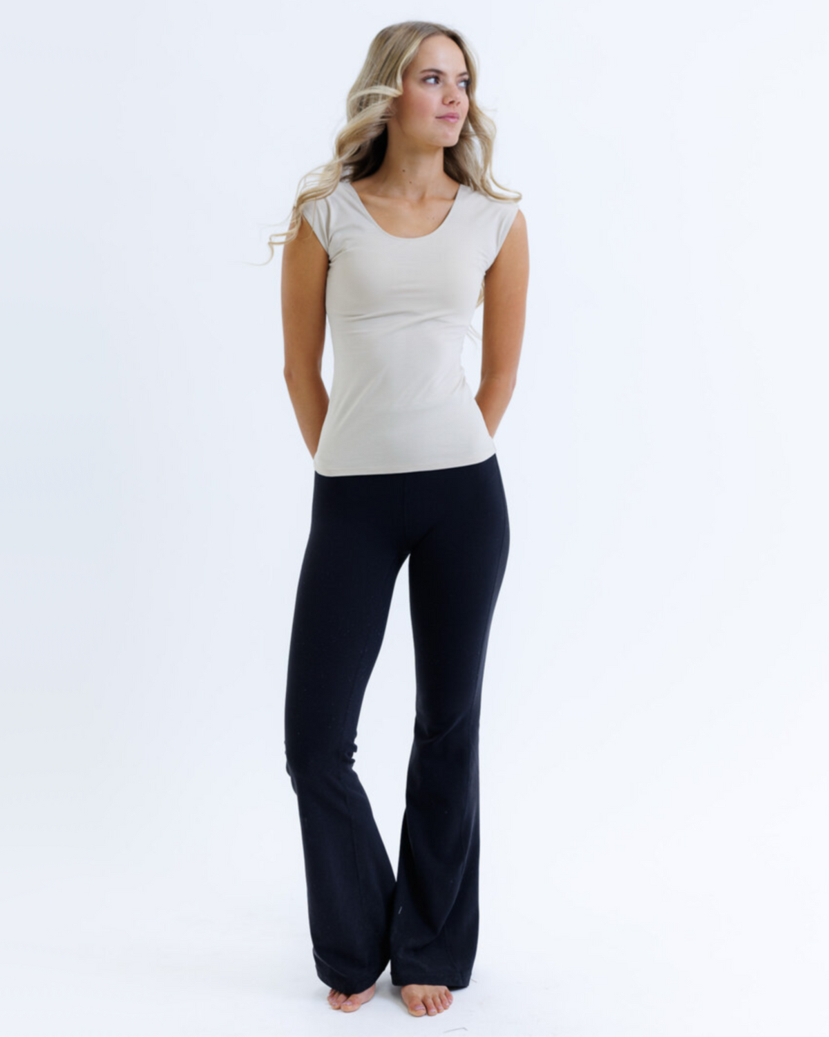 Woman wearing a white top and black pants on a white background