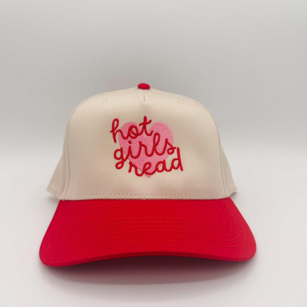 Beige and red cap with 'hot girls read' text on a light gray background