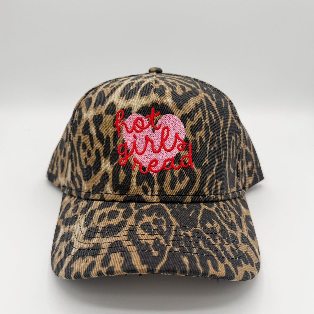 A baseball cap with a brown and black leopard print pattern, featuring a pink embroidered heart and red embroidered text reading 'hot girls read' on the front.