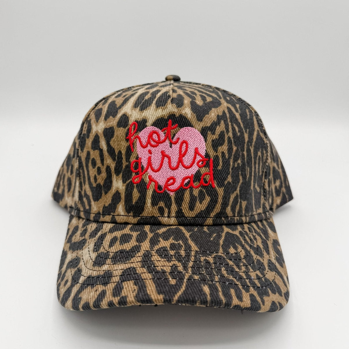 A baseball cap with a brown and black leopard print pattern, featuring a pink embroidered heart and red embroidered text reading 'hot girls read' on the front.
